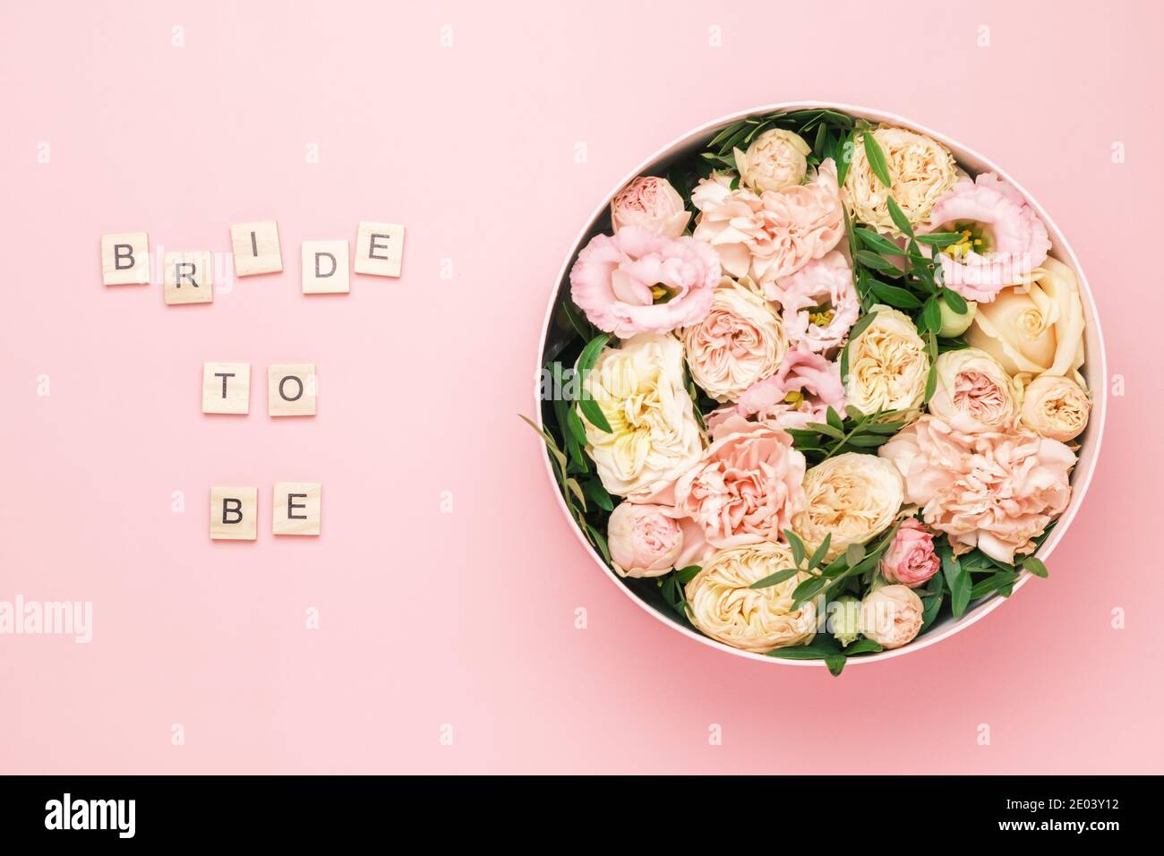 Braut zu sein Schriftzug auf den hölzernen Quadraten mit Buchstaben auf dem rosa Hintergrund und große runde Box mit roten Blumen und Rosen. Stockfoto
