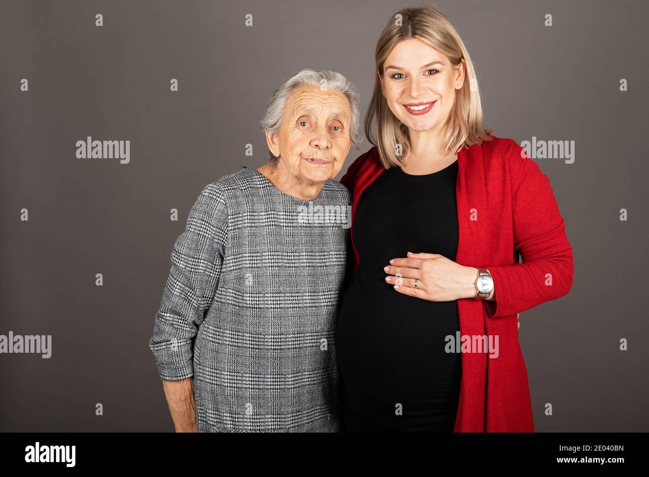 Studio Porträt der schwangeren fröhlichen Frau umarmt ältere Großmutter Stockfoto