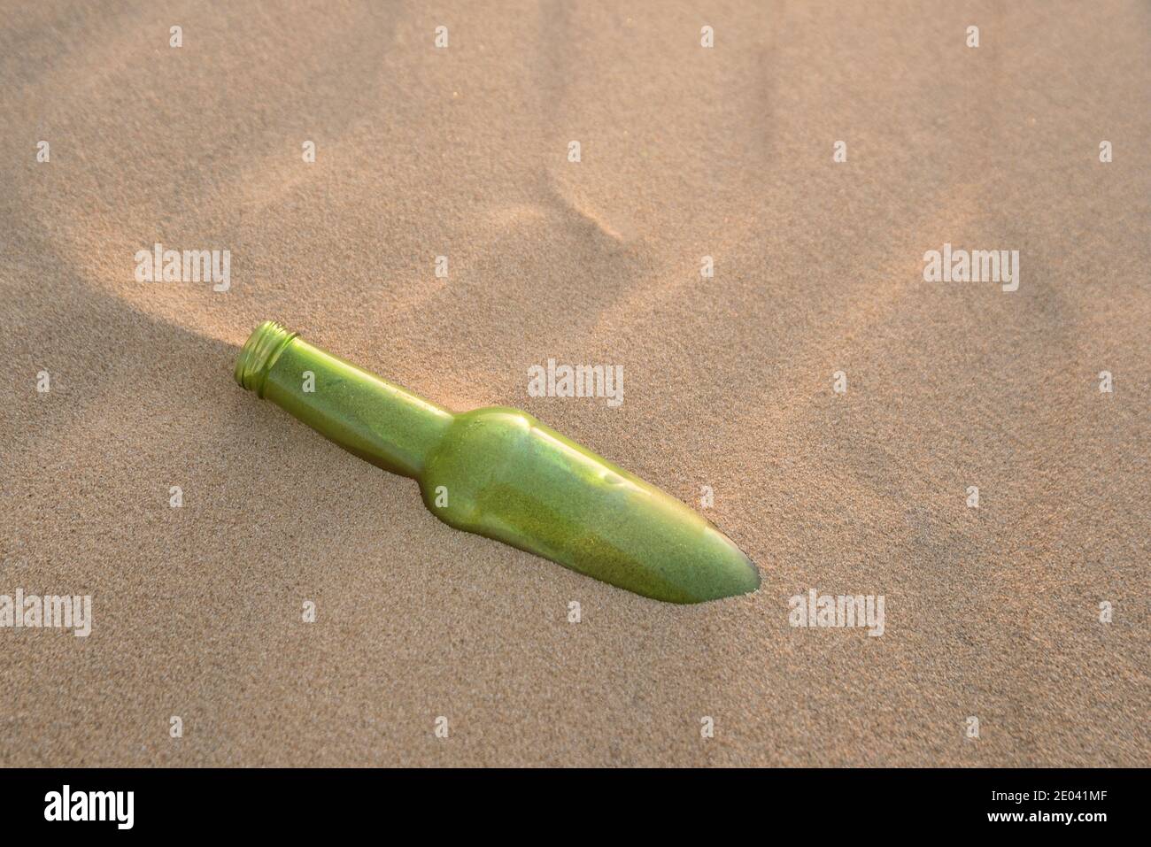 Eine Flasche halb im Sand vergraben Stockfoto