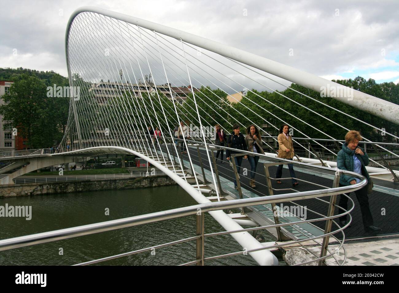 Menschen in Eile.die Zubizuri-Brücke oder Puente del Campo Volantin, ist ein gebundener Bogen Fußgängerbrücke über den Fluss Nervion . Stockfoto