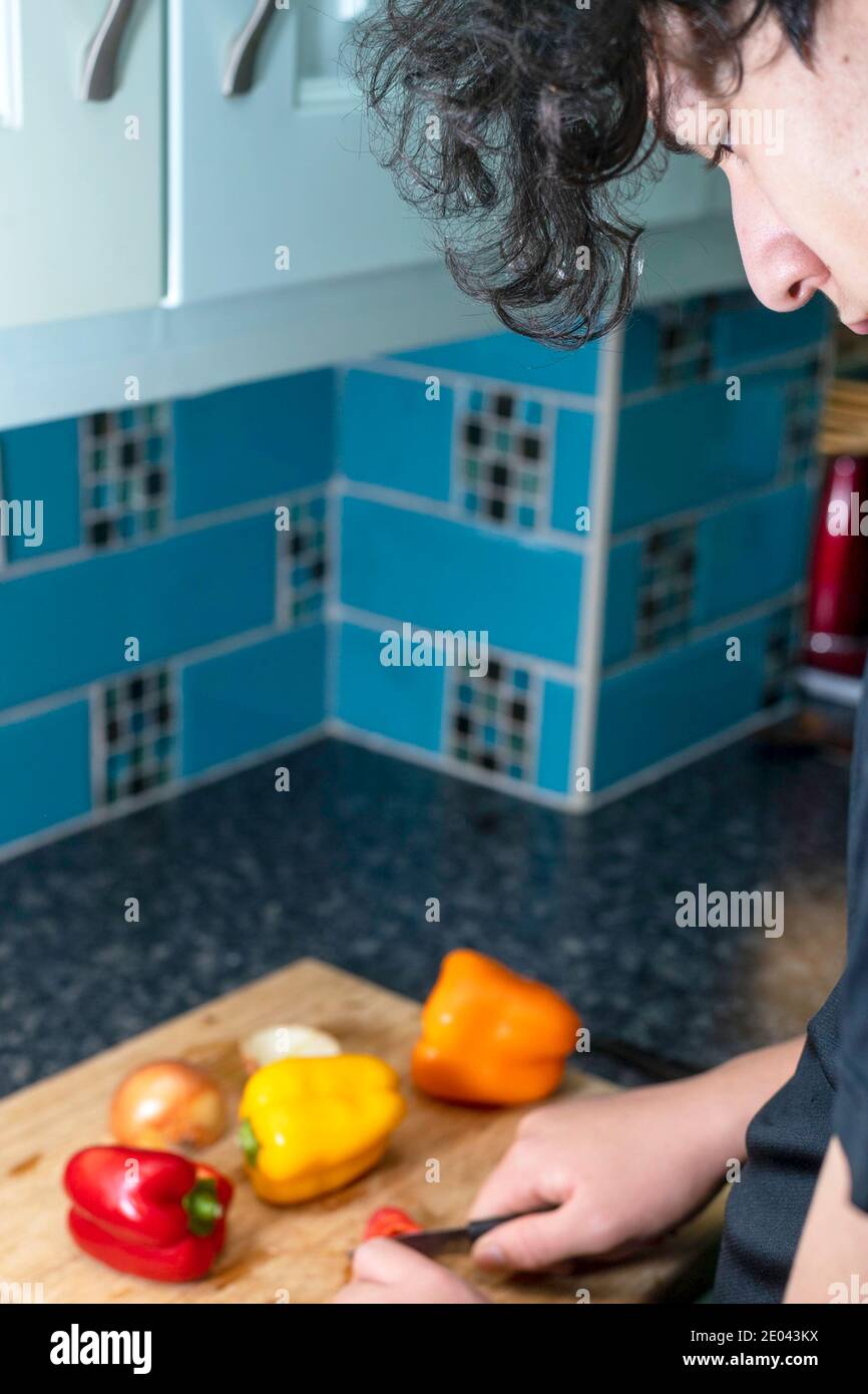 Gemischter Teenager Junge, der Essen in einer heimischen Küche zubereitet Stockfoto