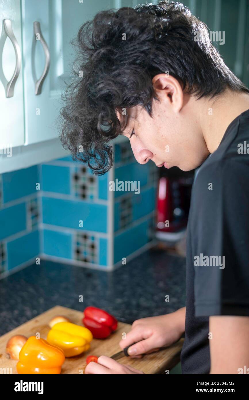 Gemischtes Rennen Teenager Junge bereitet Gemüse in der Küche Stockfoto
