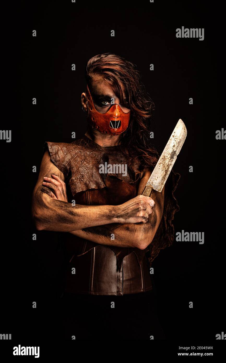 Porträt eines mörderischen Wilden in einer Ledermaske, bewaffnet mit einem Messer, das sie in der Hand hält Stockfoto