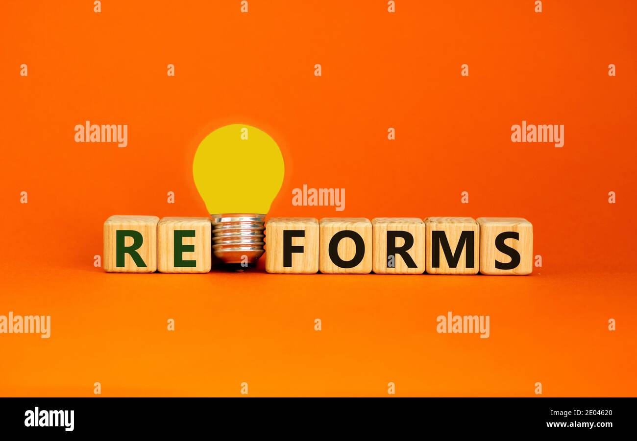Reformsymbol. Holzwürfel mit dem Wort "reforms". Gelbe Glühlampe. Schöner orangefarbener Hintergrund. Business und Reformen Konzept. Speicherplatz kopieren. Stockfoto