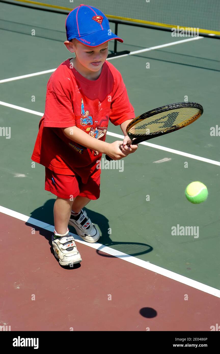 Der vierjährige Junge lernt, einen Tennisball zu hüpfen Während des Unterrichts in einer Jugendtennisklinik Stockfoto