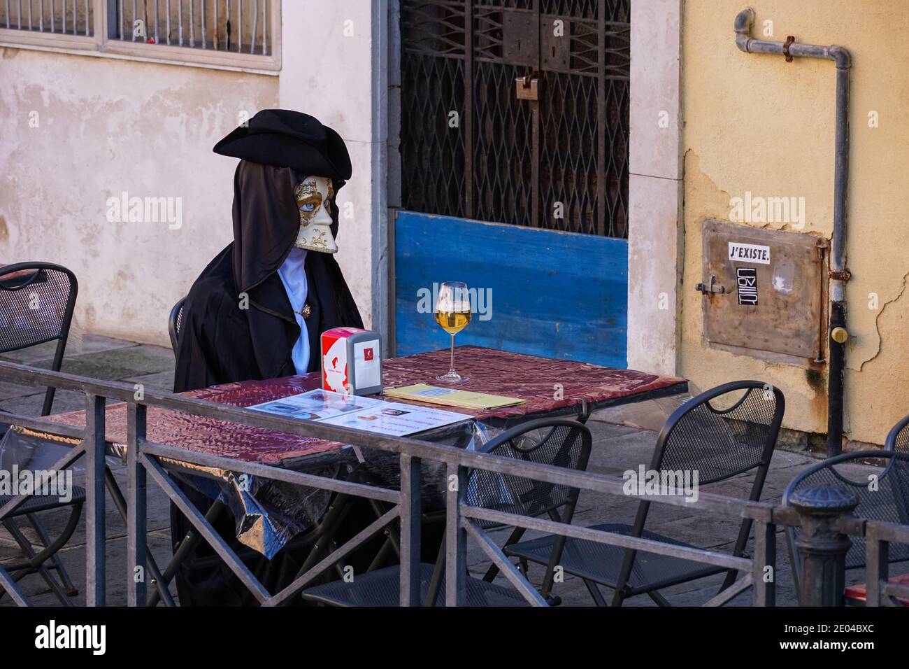 Tourist in venezianischen Kostümen sitzen allein mit einem Glas Wein in Venedig, Italien Stockfoto