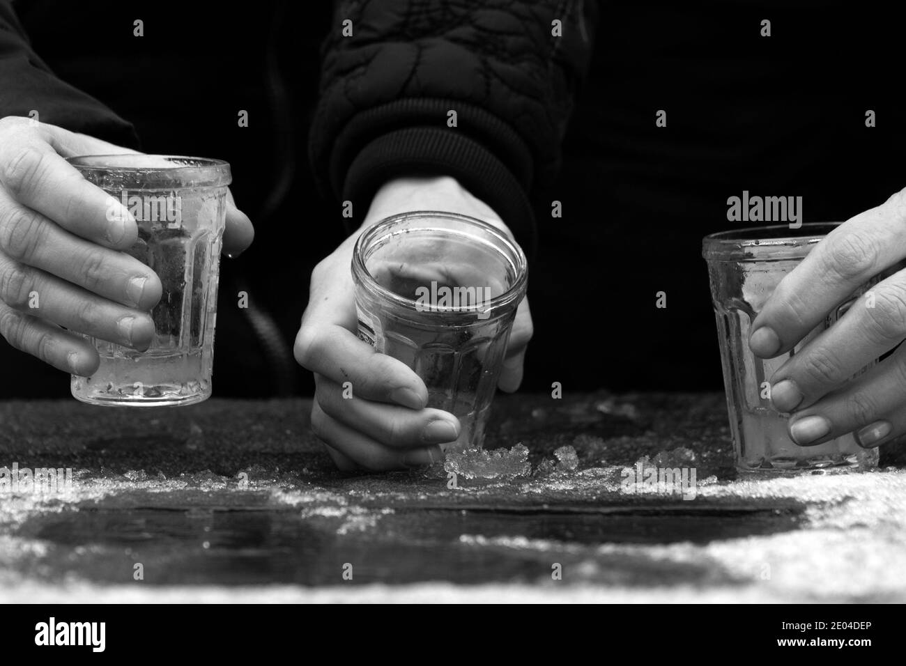 Hände von drei Frauen, die Wodka im Winter im Freien trinken Stockfoto