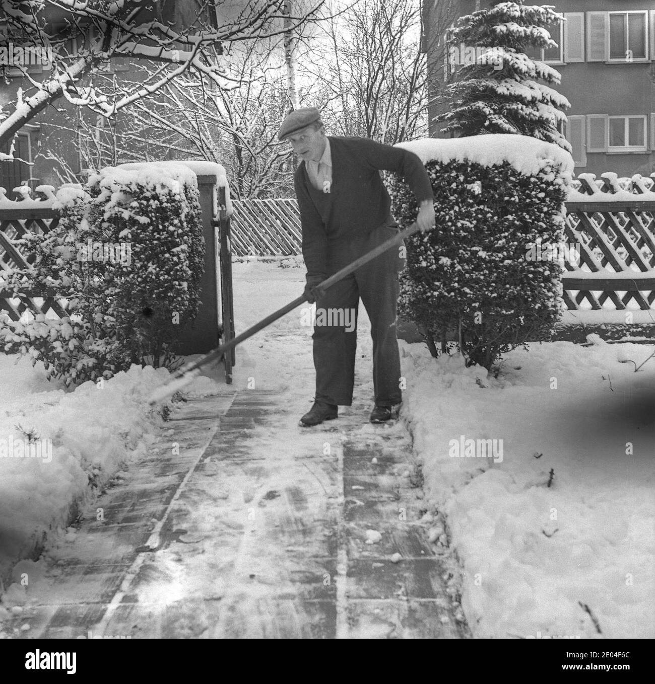 Man Shovels Schnee vom Bürgersteig, 1951, Deutschland Stockfoto