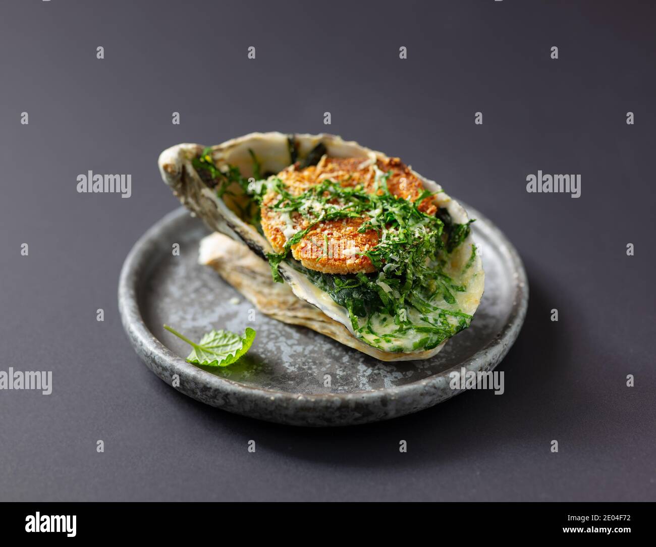 Gebackene Auster mit geröstetem Brot und Gemüse auf grauem Teller, selektiver Fokus Stockfoto
