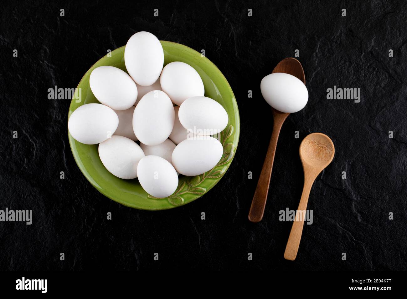 Bündel roher Eier auf grünem Teller mit Holzlöffeln Stockfoto