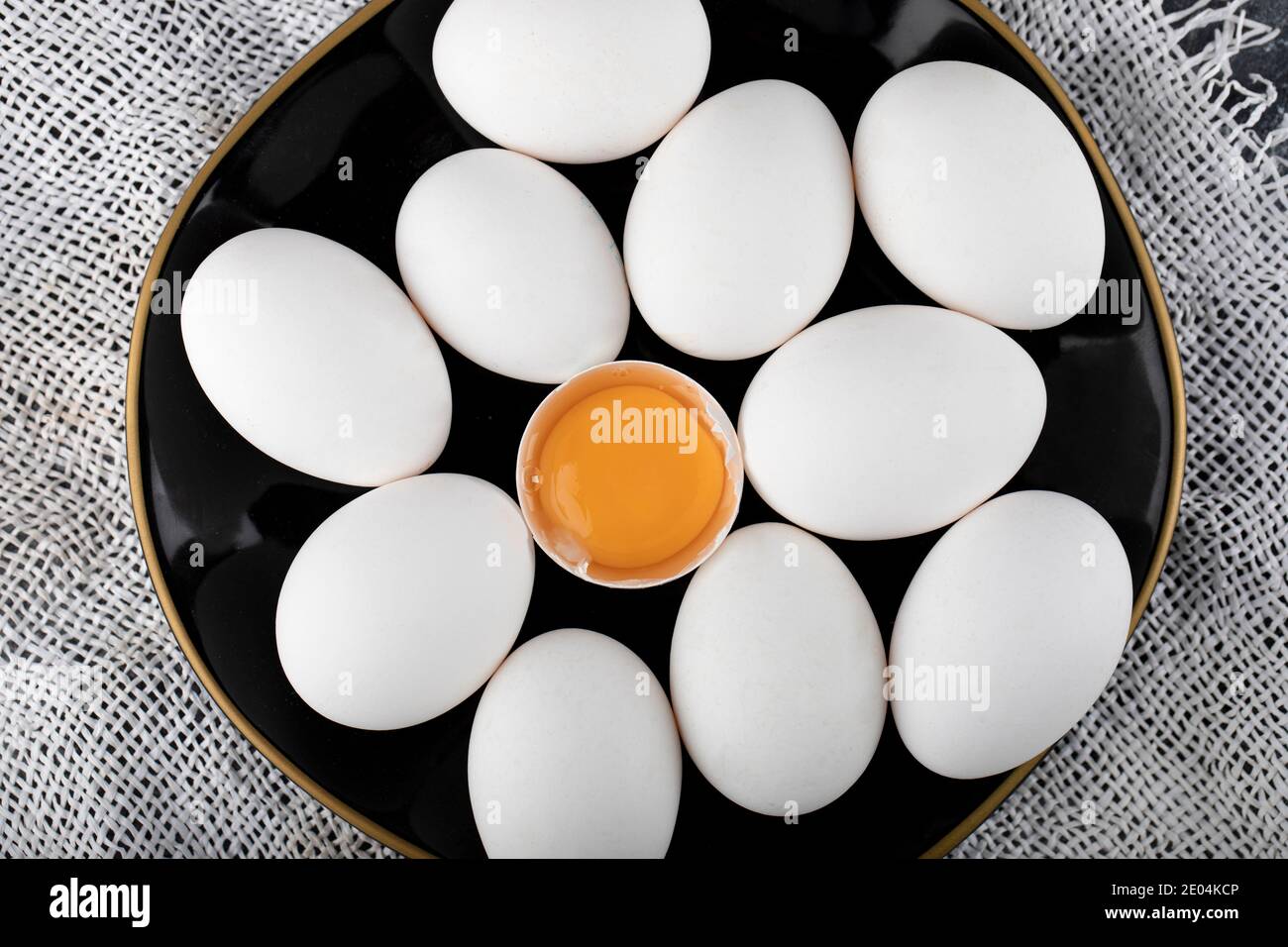 Weiße Eier und Eigelb auf schwarzem Teller Stockfoto