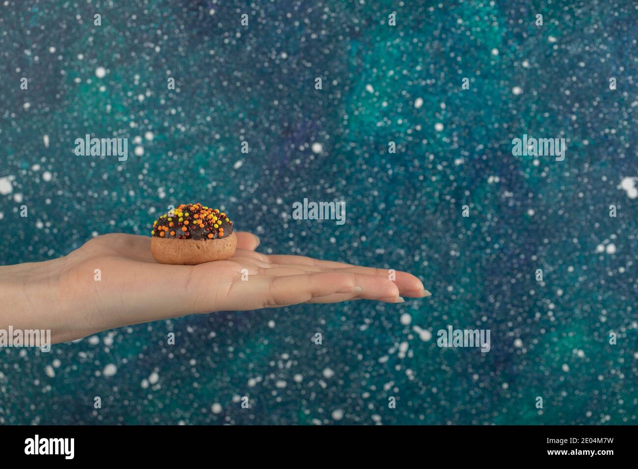 Weibliche Hand hält Cookie auf bunten Hintergrund Stockfoto