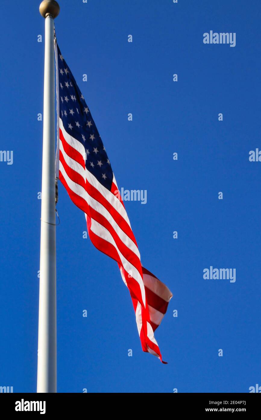 Eine amerikanische Flagge winkt sanft in einer leichten Brise gegen einen klaren blauen Himmel. Stockfoto