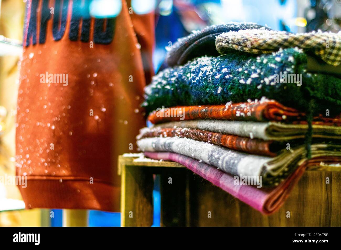 Oxford, UK -14 Dec 2020: Winterdecken und Pullover mit Schnee, alle aufeinander gestapelt, rote Tasche im Hintergrund, Ladendisplay für verschneite aber gemütliche Stockfoto