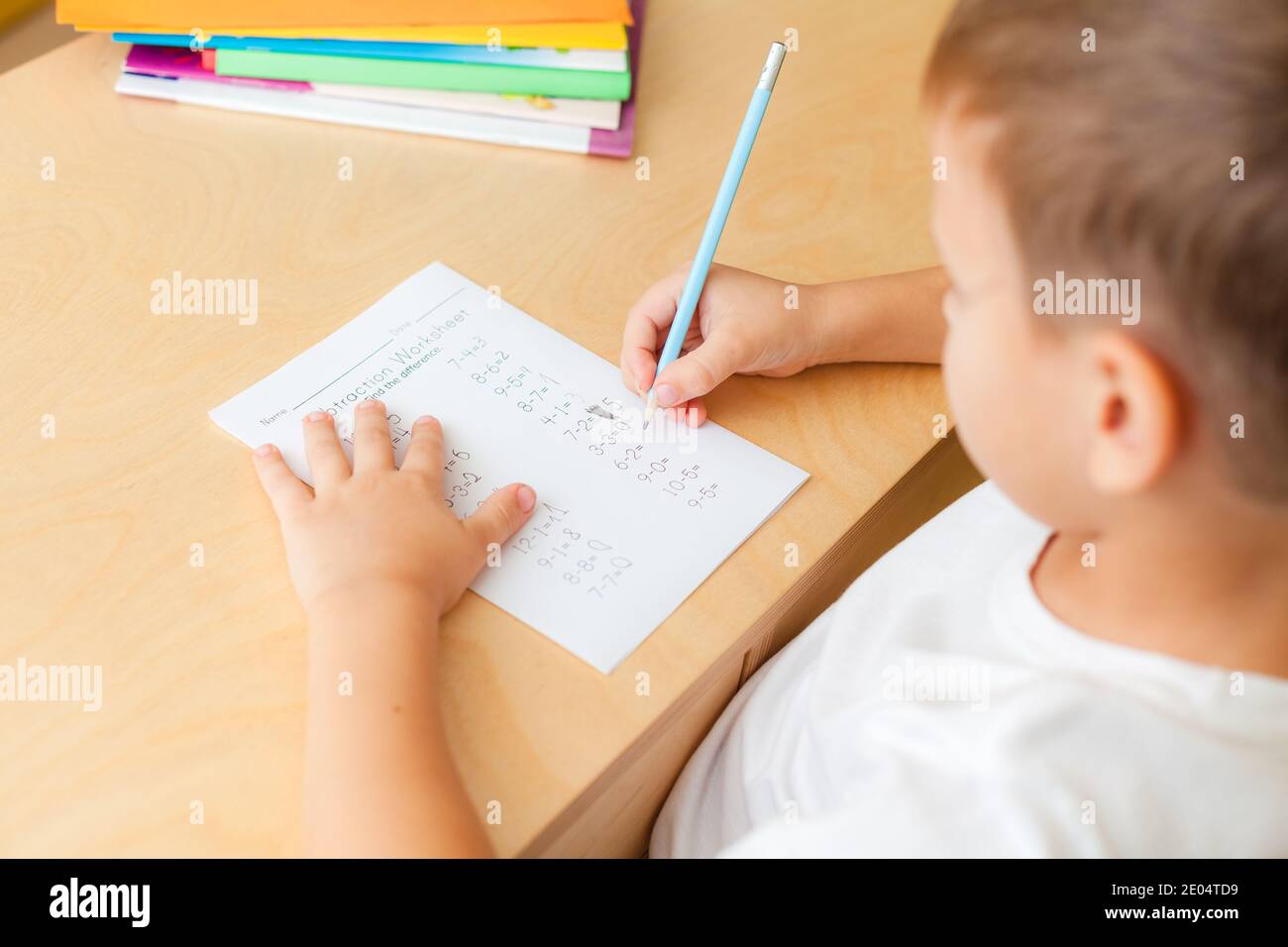 7 Jahre alter Junge macht Unterricht am Schreibtisch in seinem Zimmer. Stockfoto