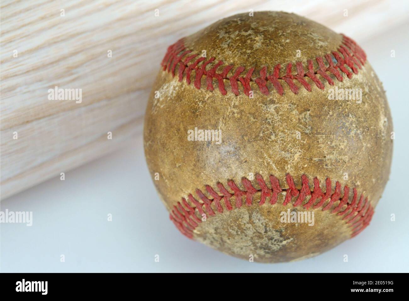 Ein alter und gut gebrauchter Baseball wird aus der Nähe gezeigt, neben einem neuen, Holz Baseballschläger. Stockfoto