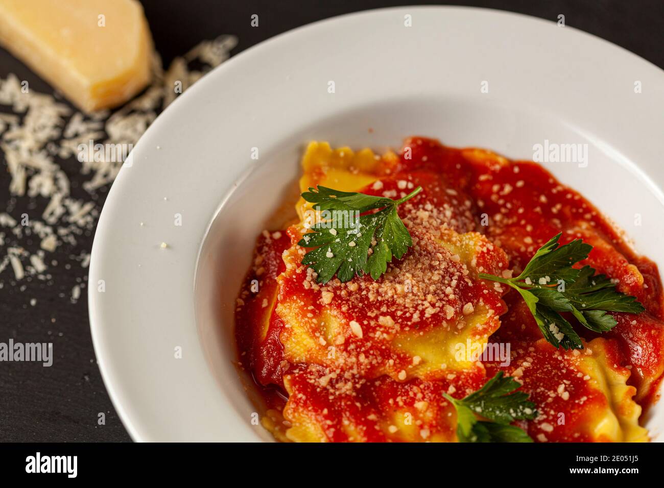 Close up Bild von weißem Porzellan Teller der italienischen Ravioli in Tomatensauce mit geriebenem Parmesan Käse und frischen grünen Petersilienblättern beendet. Ein Chee Stockfoto