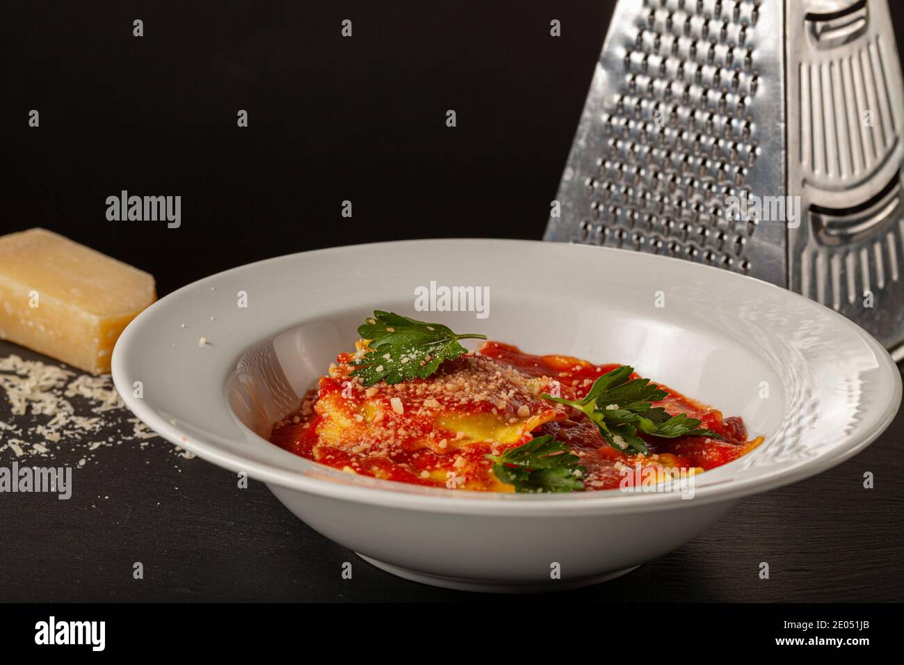 Close up Bild von weißem Porzellan Teller der italienischen Ravioli in Tomatensauce mit geriebenem Parmesan Käse und frischen grünen Petersilienblättern beendet. Ein Chee Stockfoto