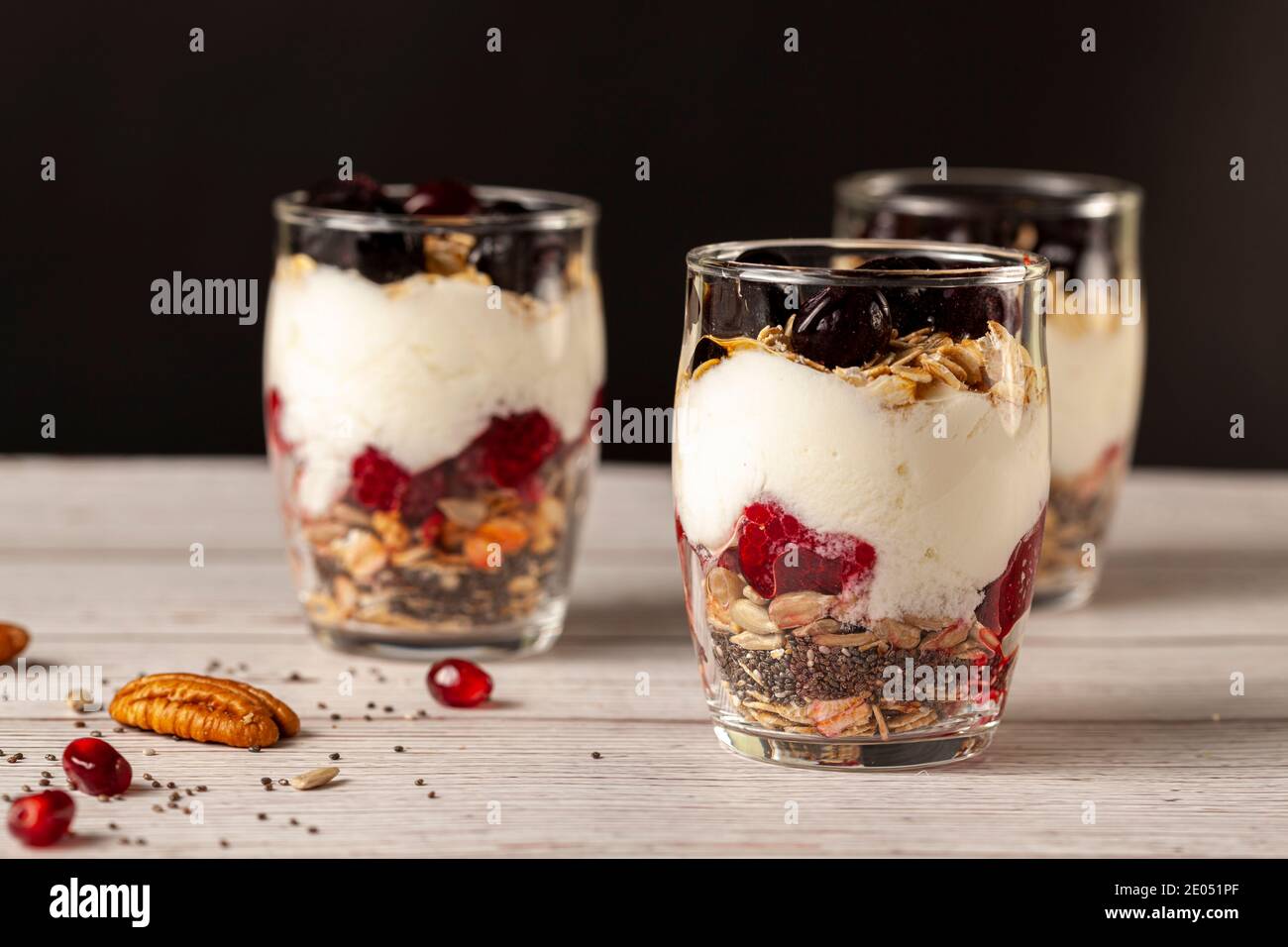 Seitenansicht von köstlichen Obst- und Joghurt-Parfait-Tassen gefüllt mit Schichten von Müsli, Chiasamen, frischen Beeren, Haferflocken und hausgemachtem Joghurt serviert Stockfoto
