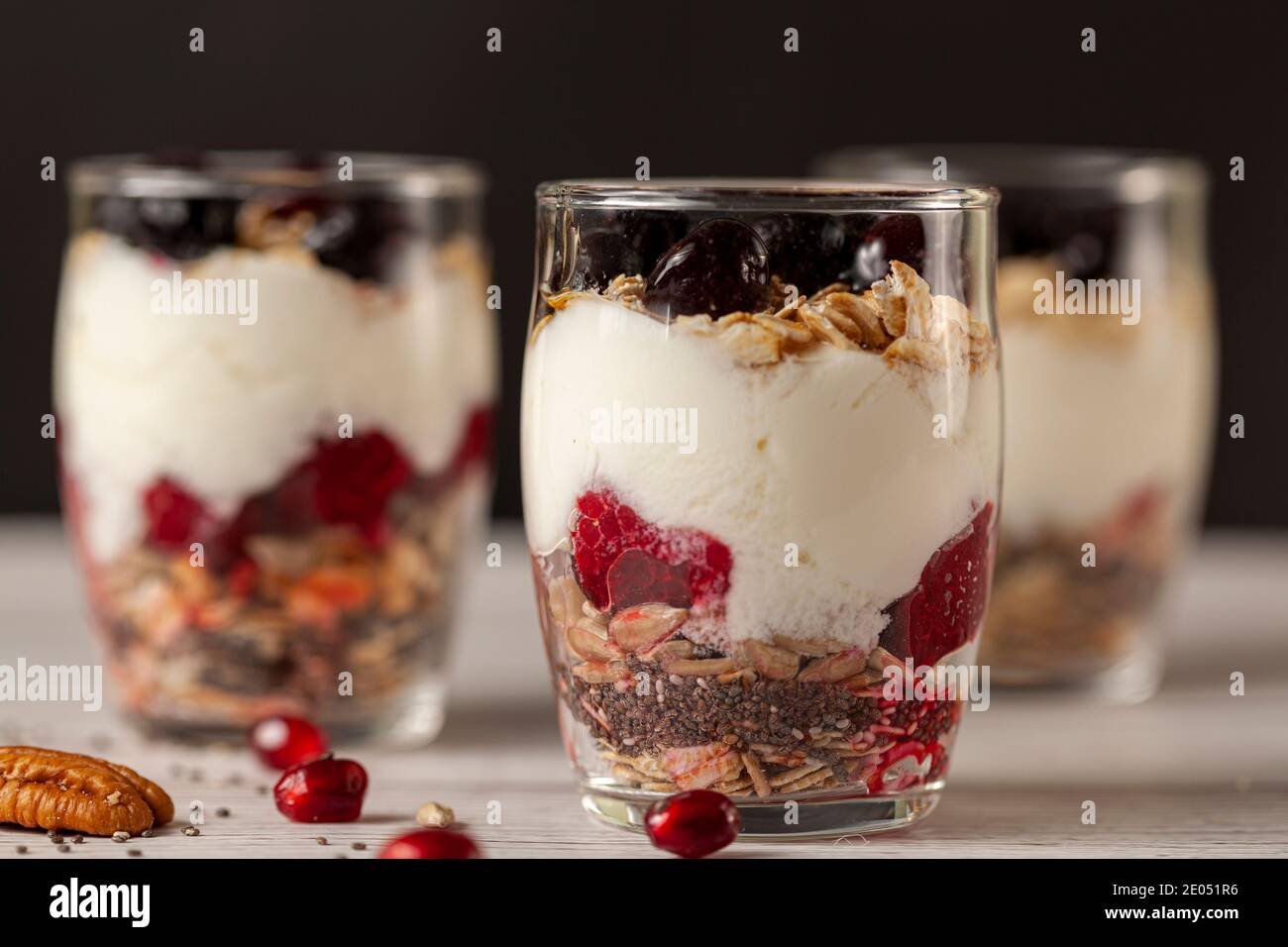 Seitenansicht von köstlichen Obst- und Joghurt-Parfait-Tassen gefüllt mit Schichten von Müsli, Chiasamen, frischen Beeren, Haferflocken und hausgemachtem Joghurt serviert Stockfoto