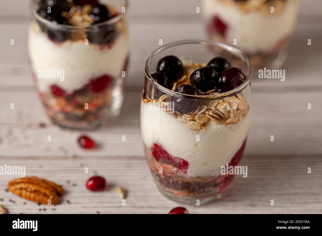 Schräg Blick auf köstliche Obst Joghurt Parfait Tassen gefüllt mit Schichten von Müsli, Chiasamen, frische Beeren, Haferflocken und hausgemachtem Joghurt serviert w Stockfoto