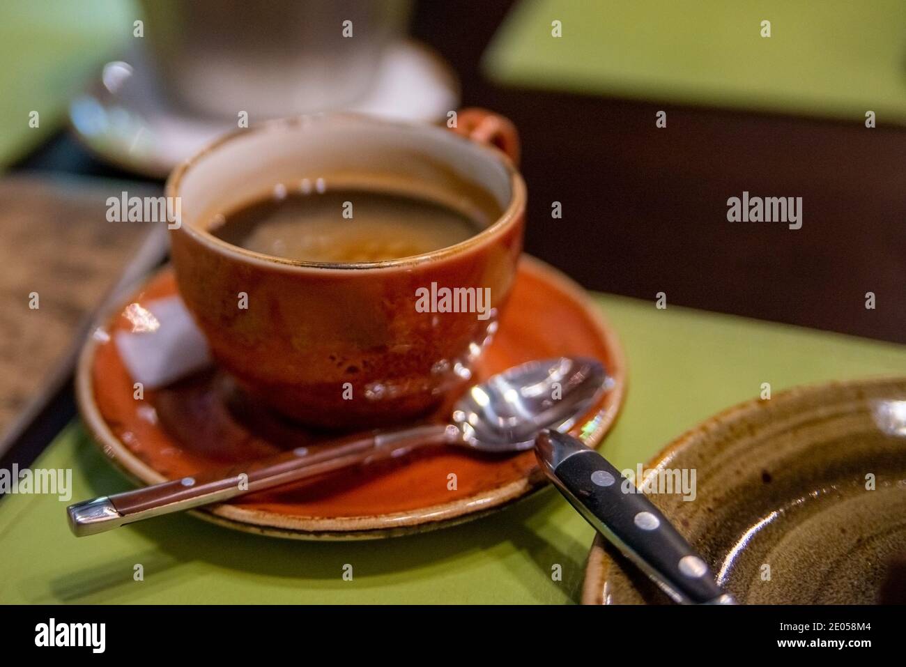 Braune Tasse mit schwarzem Kaffee auf einer Untertasse mit einem Löffel Stockfoto