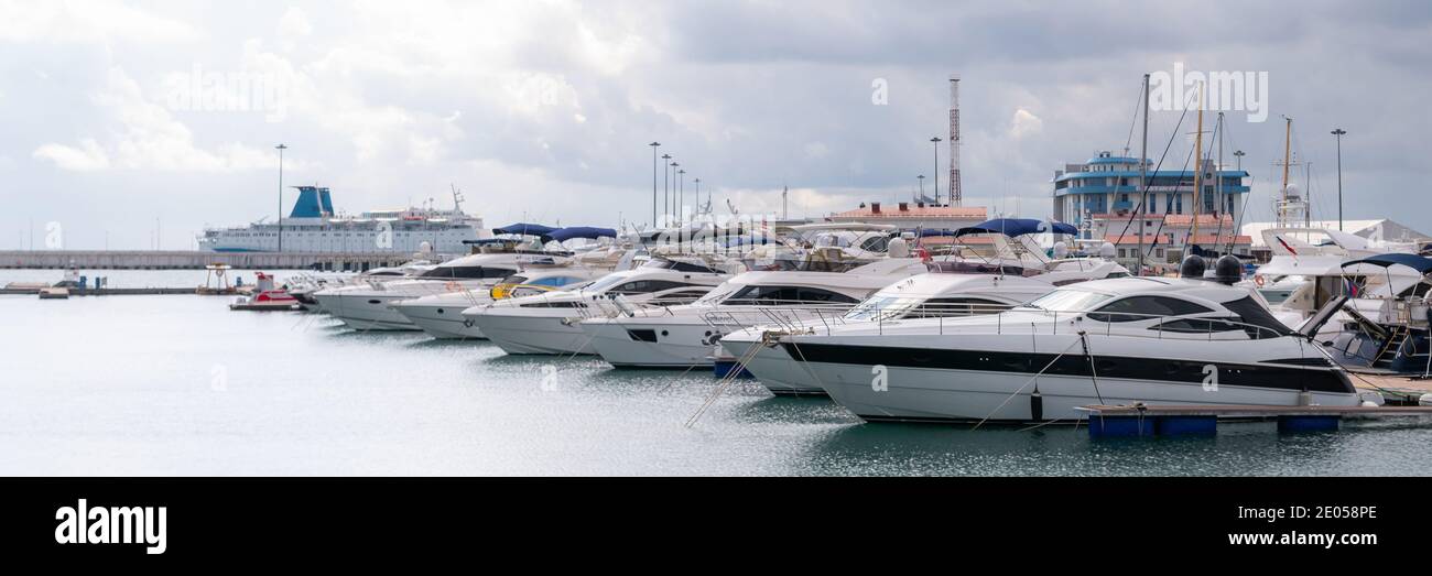 Yachten und Schnellboote am Hafen. Motorboote in Marina vertäut. Pier an der Küste. Erstklassiger Lifestyle. Yachting. Teures Spielzeug. Seeverkehr. Reise Stockfoto
