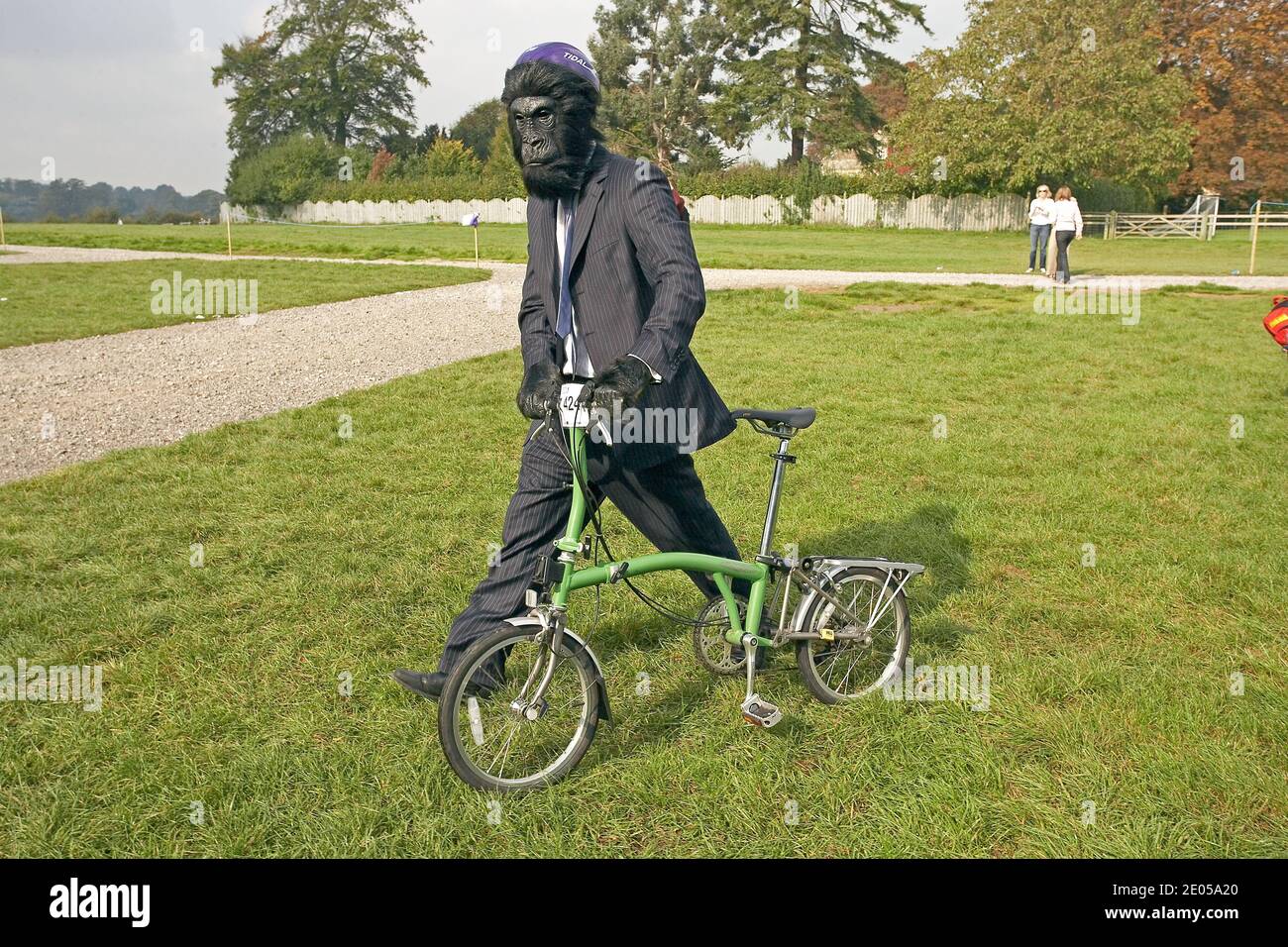 Teilnehmer in einem Affenkostüm, der sein Brompton-Faltrad bei der Brompton-Weltmeisterschaft im Blenheim Palace, Großbritannien, schiebt. Stockfoto