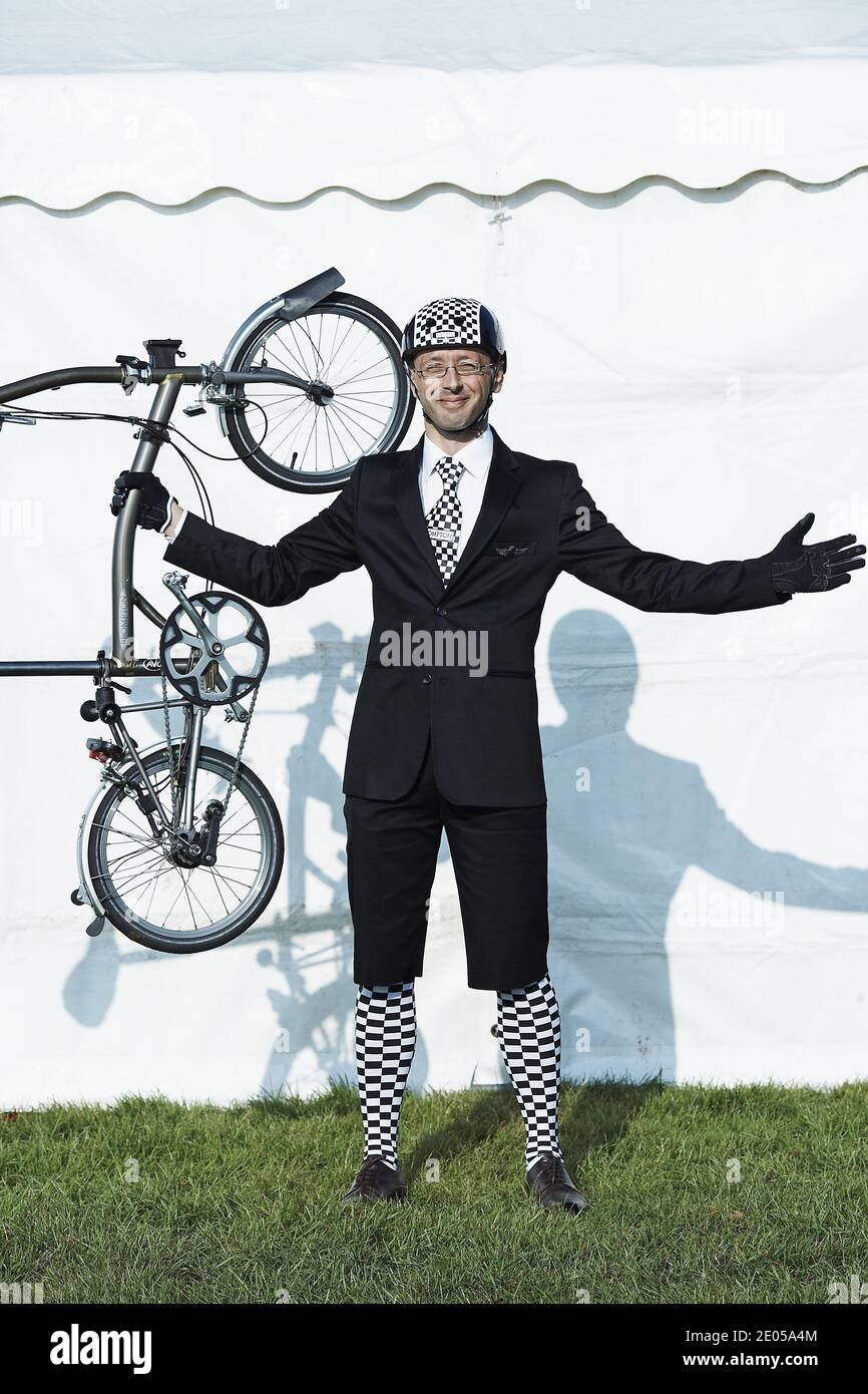 GROSSBRITANNIEN / England /Mann mit Anzug und karierter Krawatte und Socken, die Brompton Fahrrad in der Luft halten. Stockfoto