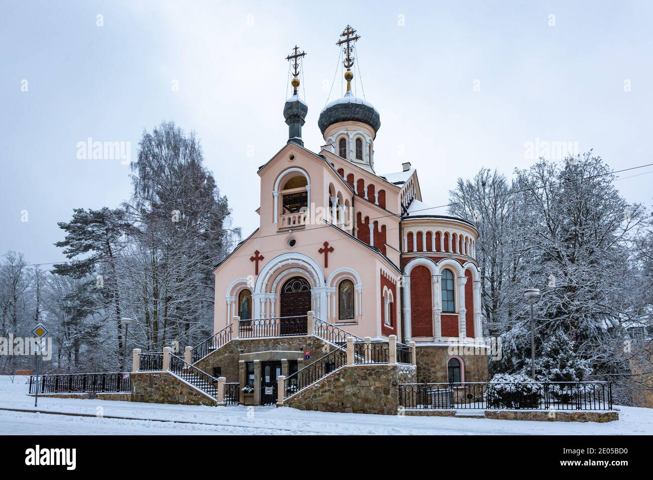 Marianske Lazne, Tschechische Republik - Dezember 29 2020: Winteransicht der orthodoxen russischen Kirche St. Vladimir mit roter Fassade umgeben von Bäumen Bucht Stockfoto