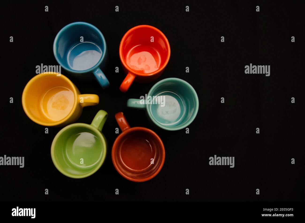 Set von bunten Kaffeetassen auf schwarzem Hintergrund Stockfoto