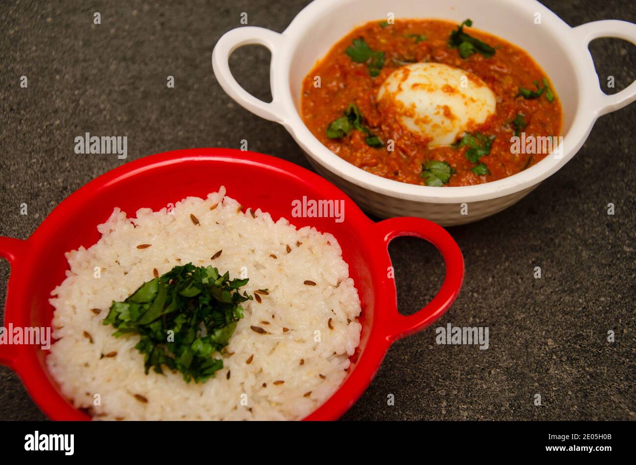 Ei-Curry in weiß gefärbte Schüssel und Reis in Rote Schale auf grauem Hintergrund Stockfoto