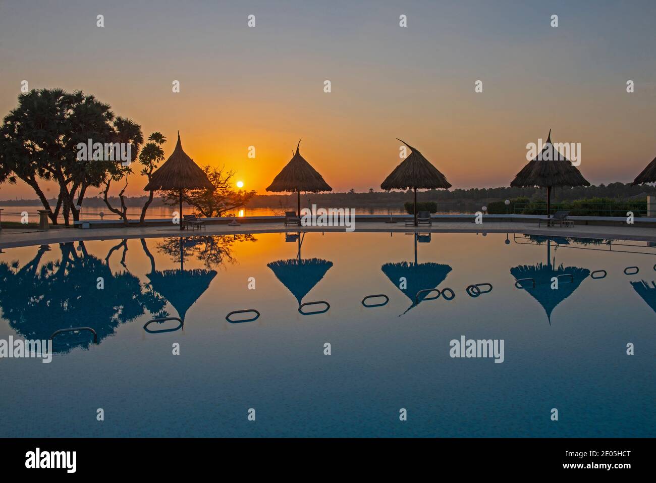 Outdoor Swimmingpool in einem tropischen Luxus Hotelresort Abenduntergang mit Reflexion im Wasser Stockfoto