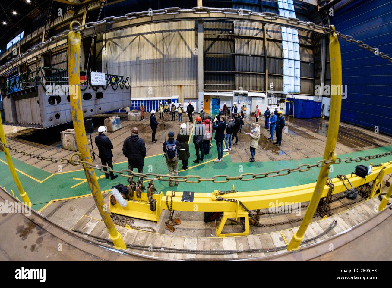 30. Dezember 2020, Schleswig-Holstein, Flensburg: Teilnehmer einer Kielverlegung stehen vor einem Unterteil eines neuen RoRo-Schiffes auf der Flensburger Werft. Mit dem Neubau hat die angeschlagene Flensburger Schiffbau-Gesellschaft (FSG) ihren ersten Auftrag seit dem Relaunch unter der Leitung der Tennor Holding erhalten. IVP Ship Invest, ein Unternehmen des Tennor-Gründers Lars Windhorst, hat eine RoRo-Fähre bestellt, teilte die FSG mit. Zudem hatte IVP Ship Invest eine Option für ein zweites Schiff platziert. Der Auftrag, einschließlich der Option, hat ein Gesamtvolumen von 140 Millionen Euro. Foto: Frank Molt Stockfoto