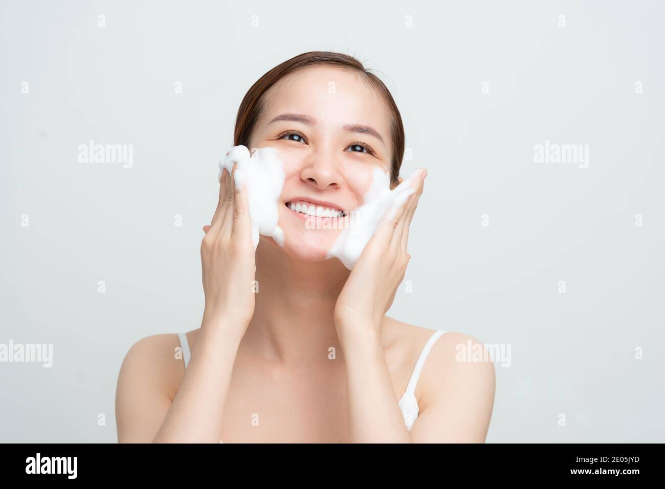 Nahaufnahme von glücklich lächelnden asiatischen Frau mit täglichen Pflege Hautreinigungsschaum und schauen erfreut, weißen Hintergrund Stockfoto