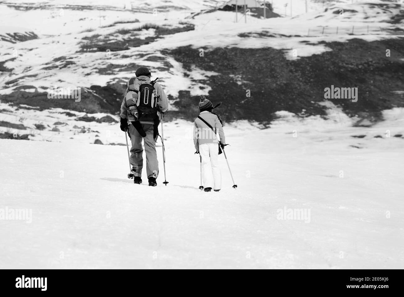 Vater und Tochter mit Skistöcken auf verschneite Piste im kleinen Schneewinter. Kaukasus, Georgien, Region Gudauri. Schwarzweißbild. Stockfoto
