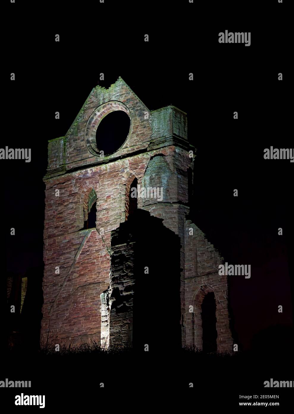 Der südliche Querschiff-Turm der Abtei Arbroath mit seinem charakteristischen runden Fenster, das an einem kalten Dezemberabend von Flutlichtern beleuchtet wird. Stockfoto