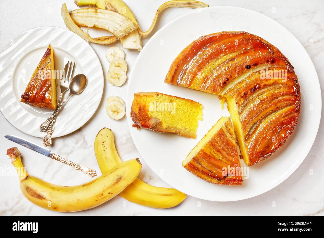 Umgedrehten Bananenkuchen auf einem weißen Teller auf einem Marmortisch, horizontale Ansicht von oben, flach liegend Stockfoto
