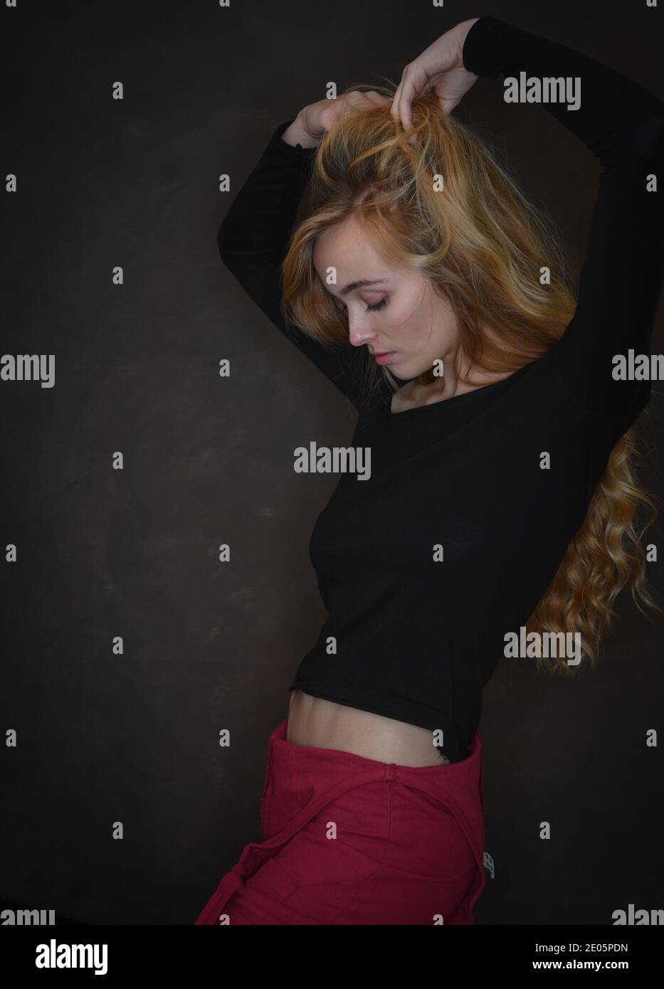 Eine gesunde, natürlich schöne junge Frau (20) mit starken Eigenschaften streckt sich nach oben und zeigt schlanke athletische Abfälle in einer selbstbewussten Pose. Stockfoto