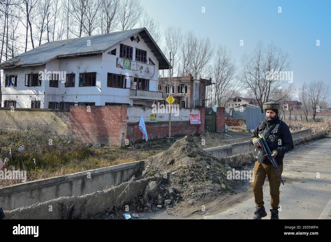 In der Nähe des beschädigten Gebäudes, in dem mutmaßliche Militante in den Außenbezirken von Srinagar Zuflucht gesucht hatten, patrouilliert eine Truppenpatrouille.drei Militante wurden bei einer nächtlichen Waffenschlacht mit Regierungstruppen im Gebiet Lawaypora in Srinagar getötet. Die getöteten Militanten planten einen großen Streik auf der Autobahn Srinagar-Muzaffarabad, sagte ein Beamter. Stockfoto