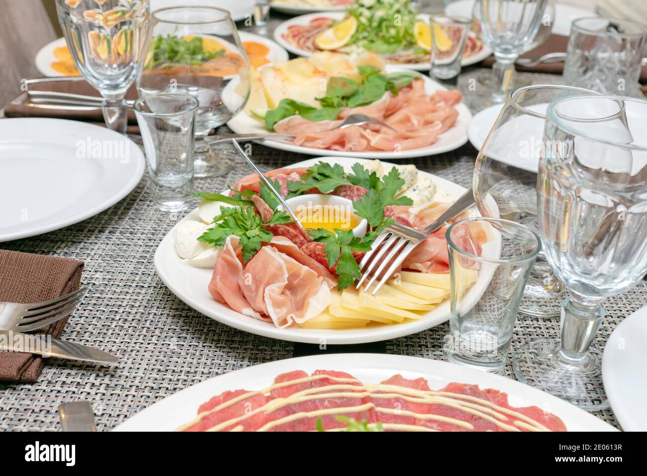 Festliche Tischstimmung, Familienessen mit italienischen Antipasti serviert - marinierter Lachs, Hamon, Carpaccio, Birne, Basilikum. Tablescape Stockfoto