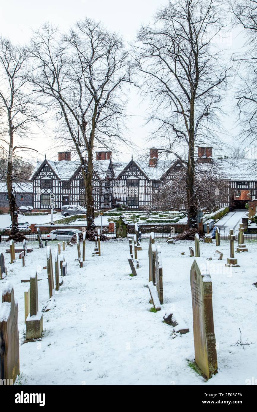 Der schneebedeckte Kirchhof und Grabsteine in der Pfarrei St. Mary kirche Sandbach Cheshire England im Winter Blick auf die Alte Hall Pub und Restaurant Stockfoto