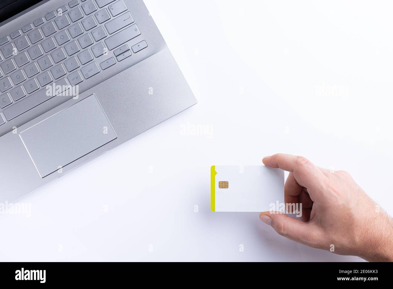 Hand halten Kreditkarte, während Online-Zahlung mit Laptop auf weißem Hintergrund. Draufsicht mit Kopierbereich. Stockfoto