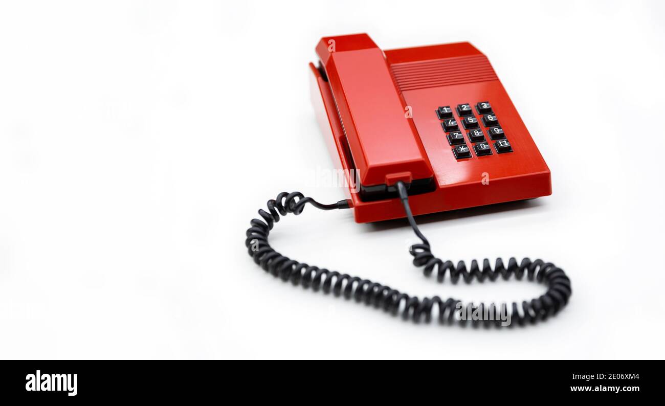 Desktop-Telefon aus den 80ern und rot isoliert auf weißem Hintergrund. Leerzeichen für Text. Kommunikationskonzept. Stockfoto