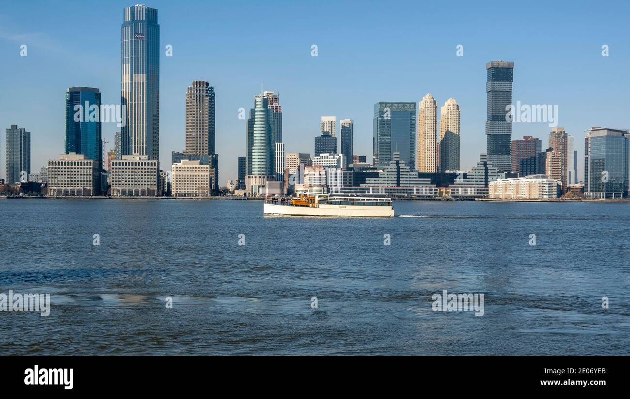New York, USA, Dezember 2020. Ein Touristenboot auf dem Hudson River mit einer Kulisse der Colgate Clock und Jersey City Hochhäuser, während der C Stockfoto