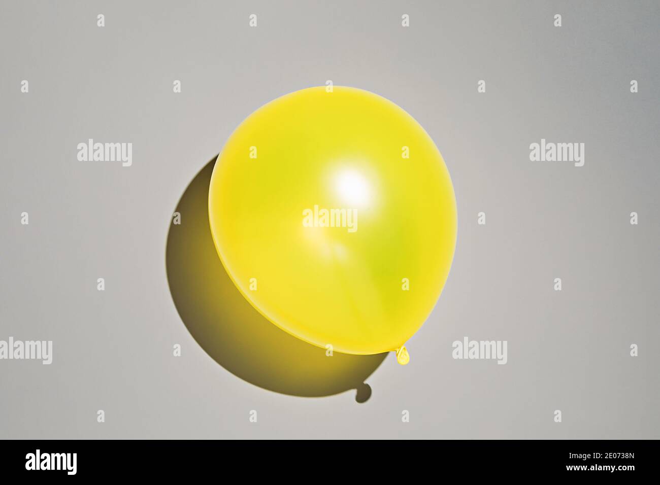 Gelber Ballon auf grauem Hintergrund. Foto in Farben des Jahres 2021 Stockfoto