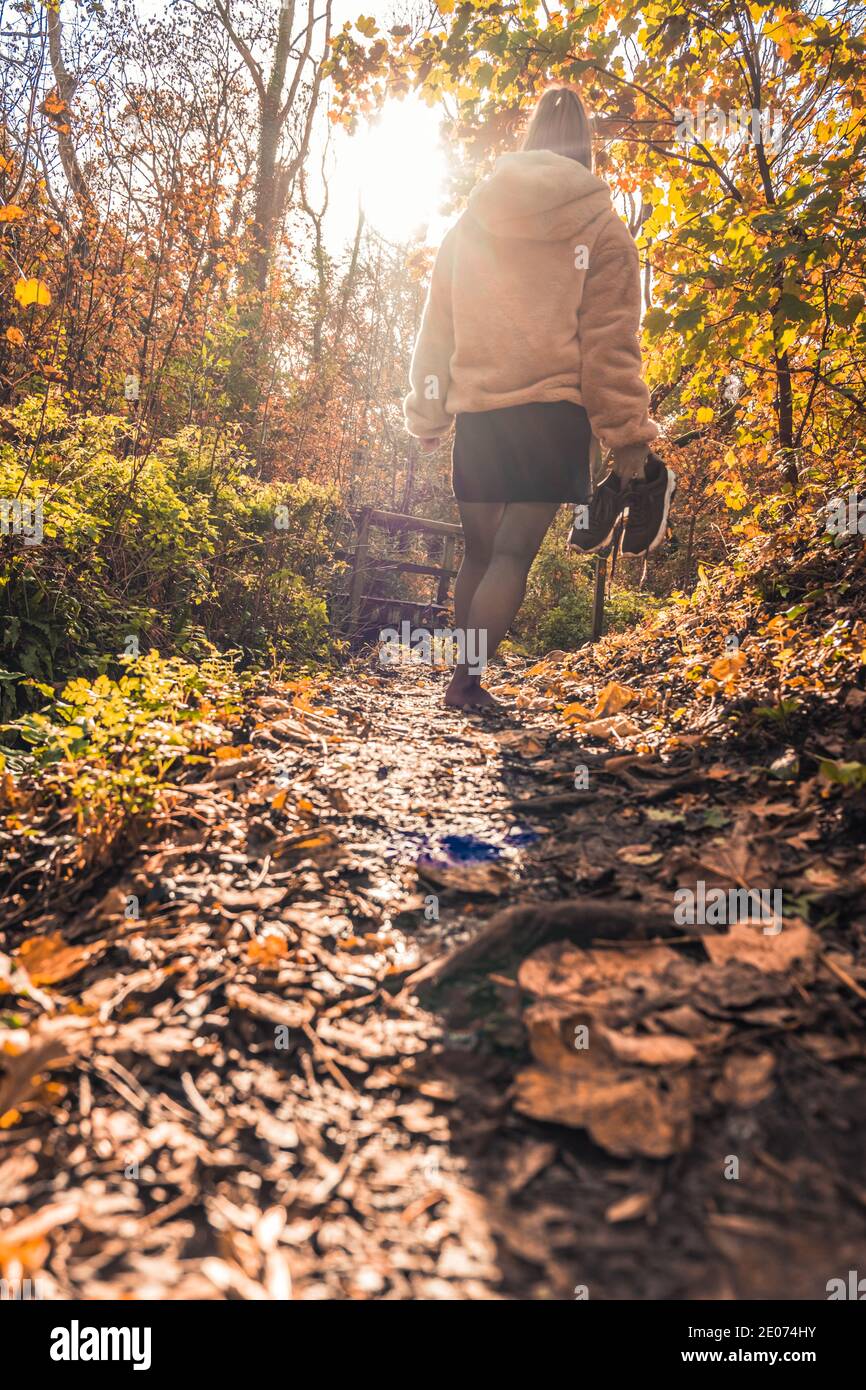 Frau, die barfuß durch den Wald läuft und ihre Turnschuhe hält Stockfoto