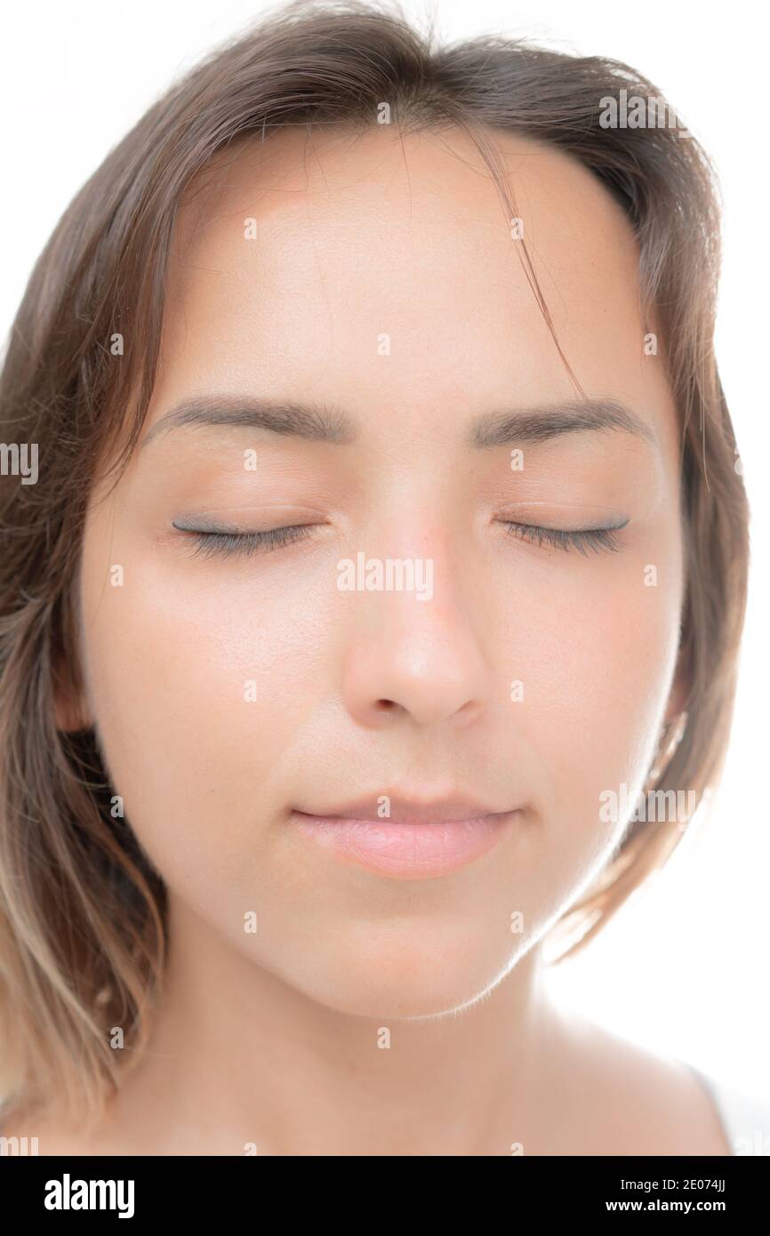 Eine junge schöne Brünette mit geschlossenen Augen und ein Leichtes Lächeln vor weißem Hintergrund Stockfoto