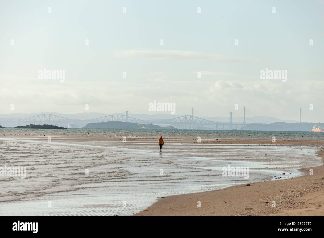 Eine Einzelperson, die alleine am Strand von Pettycur Bay, Fife, Schottland entlang läuft. Stockfoto