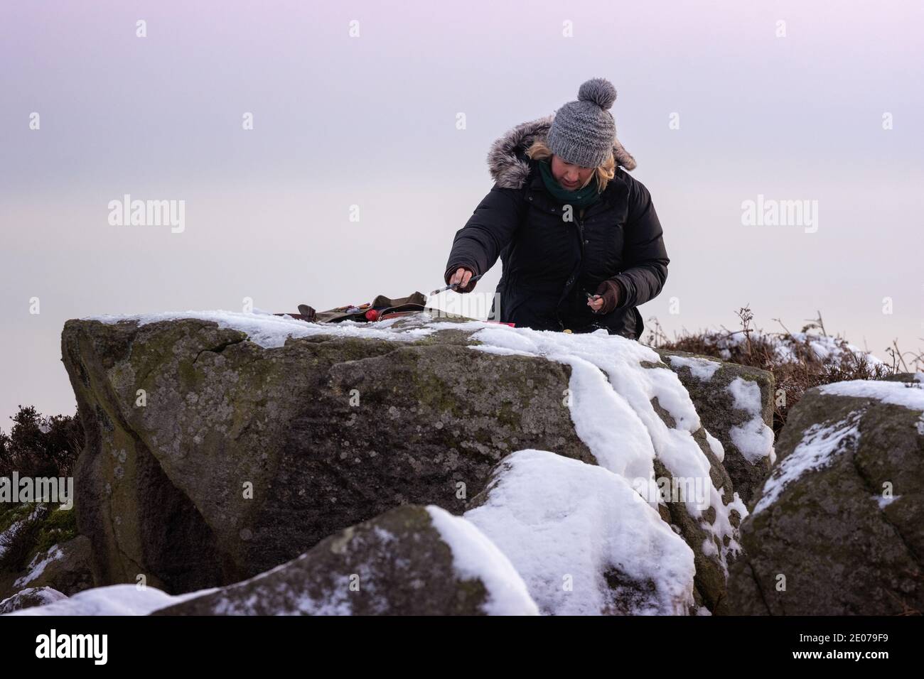 Junge Künstlerin Malerei, en plein air, eine Landschaft im Freien im Schnee auf Ilkley Moor an einem winterlichen Tag, West Yorkshire, England, Großbritannien Stockfoto